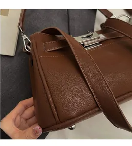 Detail of soft brown pebble leather handbag with silver buckle and metallic bottom studs