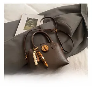 Detail der dunkelbraunen Retro-Muscheltasche mit Metalldrehverschluss und Holzperlen