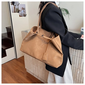 Detail showing the slouchy suede texture and slender shoulder strap of this tote bag