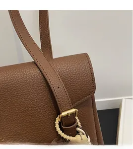 Détail du sac cabas en cuir grainé marron avec boucle dorée et texte fashion élégant