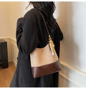 Detail of suede bucket bag with brown leather base and decorative wooden beads