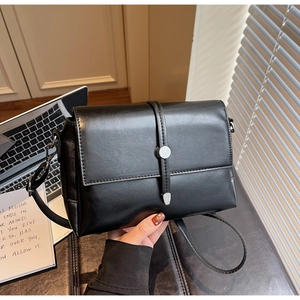 Detailed shot of a black leather crossbody bag with silver circular lock and shoulder strap
