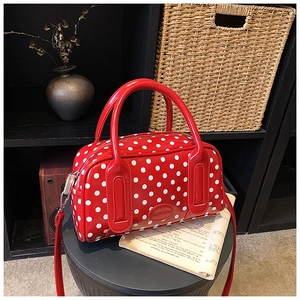 Close-up of red polka dot handbag with dual handles and adjustable shoulder strap
