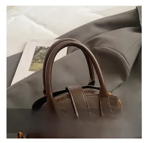 Detail der dunkelbraunen Leder-Muscheltasche mit Goldbeschlägen und Perlenanhänger