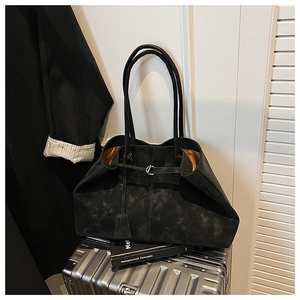 Detail of black vintage tote bag with orange lining resting on silver luggage case