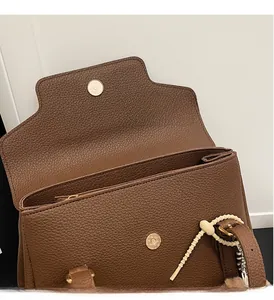 Gros plan du sac bandoulière en cuir marron avec boucle magnétique dorée haut de gamme