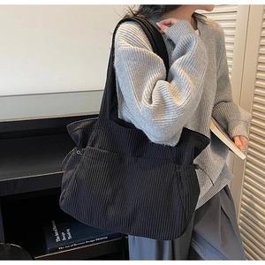 Model wearing black corduroy tote bag with drawstring details for a casual look