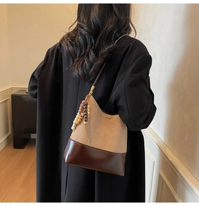 Detail of color-block suede hobo bag with vintage wooden beads on black wool coat
