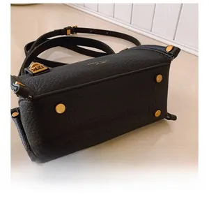 Detail der Basis einer schwarzen Kieselleder-Tasche mit vier goldenen Schutznägeln aus Metall