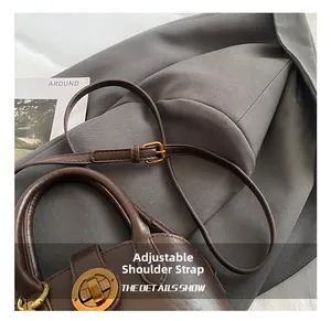 Detail der dunkelbraunen Leder-Muscheltasche mit goldenem Schloss und Schultergurt