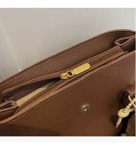 Détail de la fermeture éclair dorée et du fermoir magnétique sur le sac fourre-tout brun