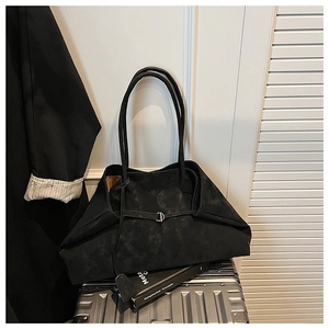 Detail of black faux leather tote bag with matte texture on silver suitcase