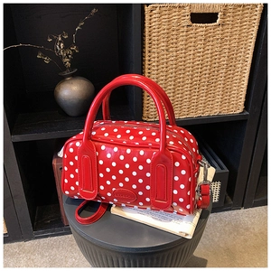 Close-up of vibrant red polka dot satchel with glossy finish and logo detail
