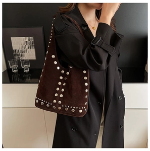 Borsa hobo scamosciata marrone scuro con borchie argentate su modella in cappotto