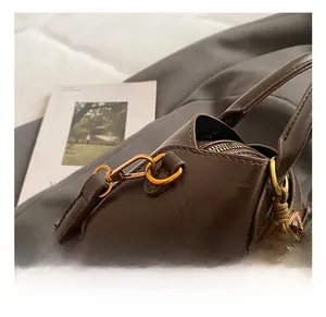 Nahaufnahme einer braunen Ledertasche mit goldenen Haken und dekorativen Perlenanhängern