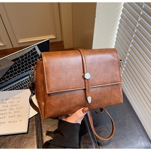 Close-up of brown PU leather shoulder bag with vintage flap and silver metal buckle