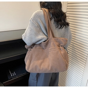 Brown corduroy tote bag shown on shoulder featuring side drawstring details and large capacity