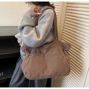 Detail of a large brown corduroy tote bag showing textured fabric and drawstring sides
