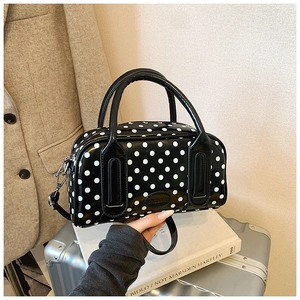 Detailed view of black polka dot handbag with dual handles and elegant shoulder strap