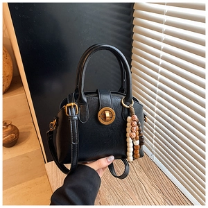 Details einer Vintage schwarzen Muschel-Ledertasche mit Goldschloss und Holzperlen