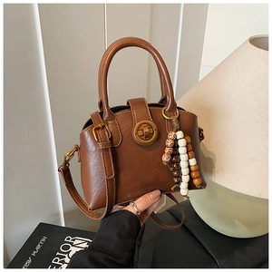 Detail der braunen Vintage-Tasche mit bunten Holzperlen-Quasten und Goldverschluss