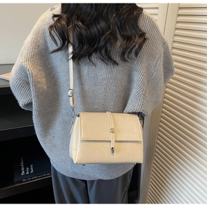 Detailed back view of a beige crossbody bag with adjustable strap on a grey sweater