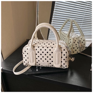 Polka dot pillow bag shown with leather handles and metallic brand logo detail