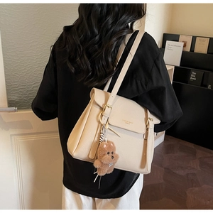 Détail du sac cabas crème en cuir grainé avec charm ours sur une bandoulière d'épaule