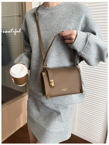 Detail of brown litchi pattern leather bag with gold twist lock and brand logo