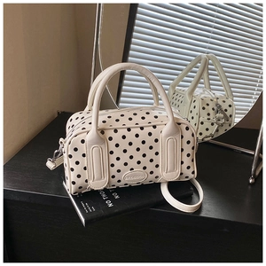 Detailed view of white polka dot boston bag on books with blinds shadow lighting