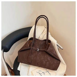 Macro view of textured dark brown tote bag with metal buckle and long shoulder straps