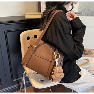 Détail d'un sac cabas en cuir marron avec boucles dorées et pendentif chiot