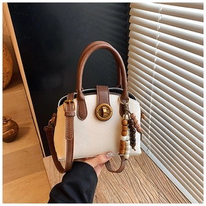 Nahaufnahme der Retro-Muscheltasche mit Metalldrehverschluss und Perlenquasten-Detail