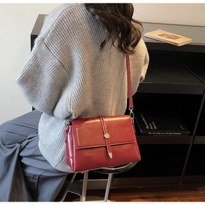 Detail view of burgundy leather crossbody bag with metal buckle and vertical strap