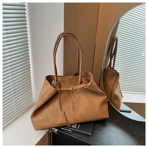 Detail of the brown matte leather tote bag featuring a pleated design and magnetic closure