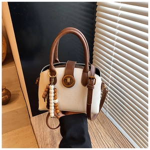 Detailaufnahme einer zweifarbigen Henkeltasche mit Vintage-Schloss auf Holzoberfläche