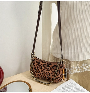 Detailed view of leopard print faux suede bag with golden chain and beaded charm details