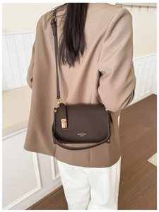 Detail of dark brown leather crossbody bag with golden metal buckle and adjustable strap