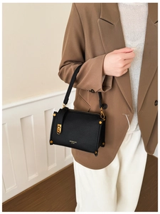 Close-up of black leather handbag with lychee grain texture and gold metal hardware detail