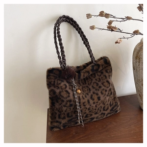 Detail of leopard print faux fur tote bag with braided handles and plush charm