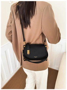 Detail of black leather crossbody bag with litchi texture and gold hardware logo