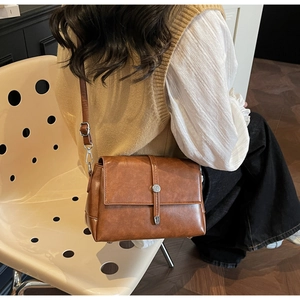 Detail of a brown vintage leather shoulder bag with a silver buckle and strap