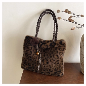 Detail view of plush leopard print tote bag with woven handles and furry charm