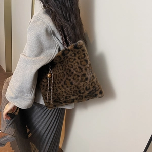 Detail of leopard print plush tote bag with woven strap and a decorative bell charm