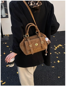 Close-up of retro brown crossbody bag with metal buckle and cute plush pendant