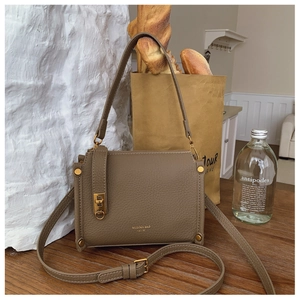Detail of lychee textured leather square handbag with gold rivets and brand logo