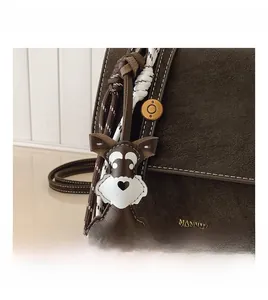 Detail of dark brown pebble leather bag with cute schnauzer dog charm and gold logo