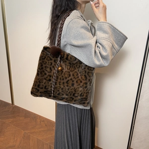 Detail of leopard print faux fur tote bag with woven strap and decorative pompom charm