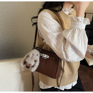 Detail of dark brown leather shoulder bag with silver buckle and plush bunny charm