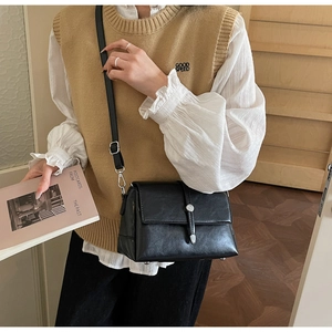 Lifestyle view of a vintage black faux leather crossbody bag with a metal buckle decoration